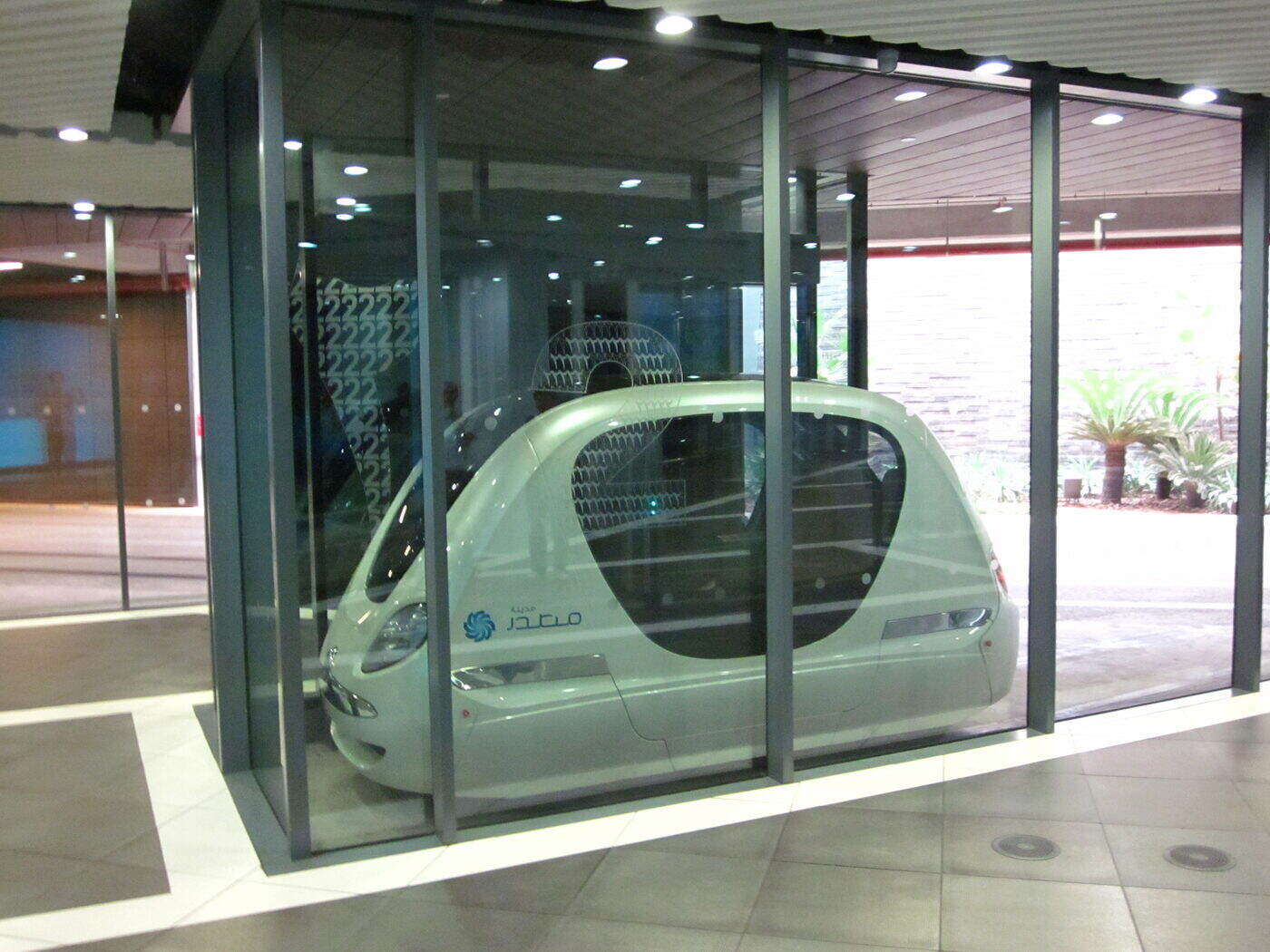 A Masdar City personal rapid transit pod displayed behind glass.