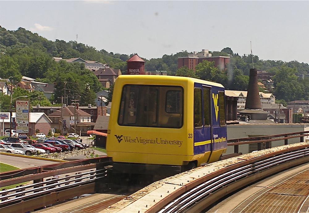 A yellow and blue West Virginia University Personal Rapid Transit vehicle on the Morgantown guideway.