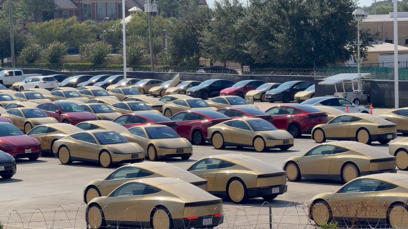 Gold Tesla Cybercabs and Model Ys packed in a fenced Houston Robotaxi lot.