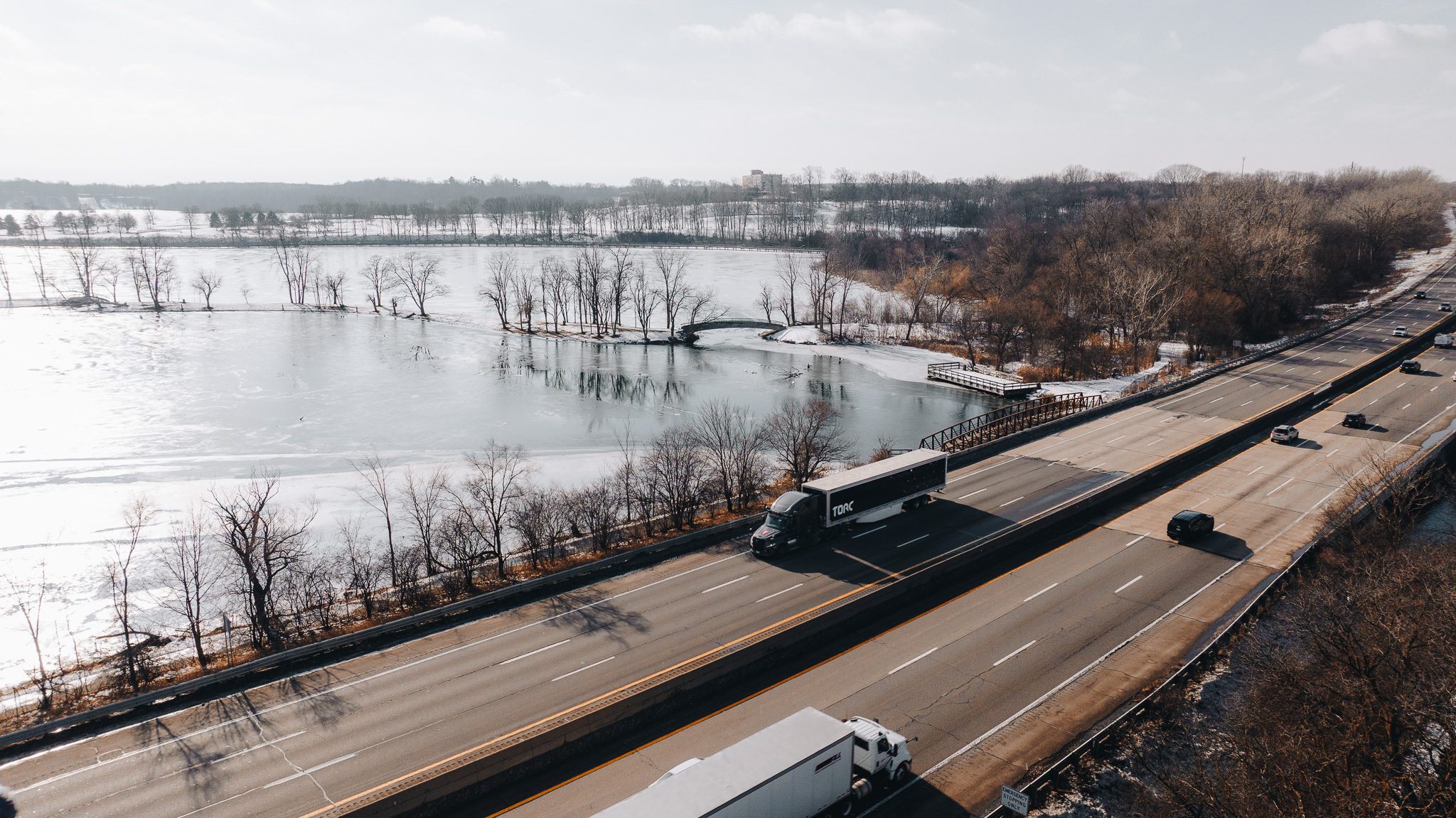 A Torc tractor-trailer on a snow-lined U.S. highway beside a frozen lake.