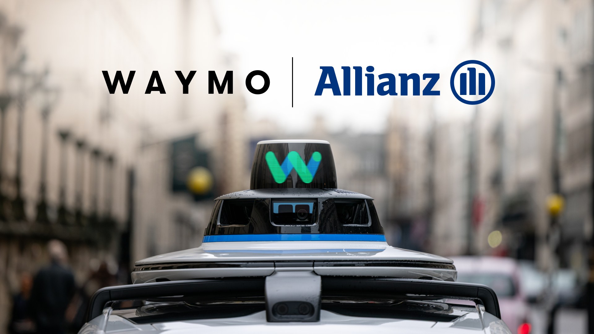 Waymo roof sensor on a city street with Waymo and Allianz logos.