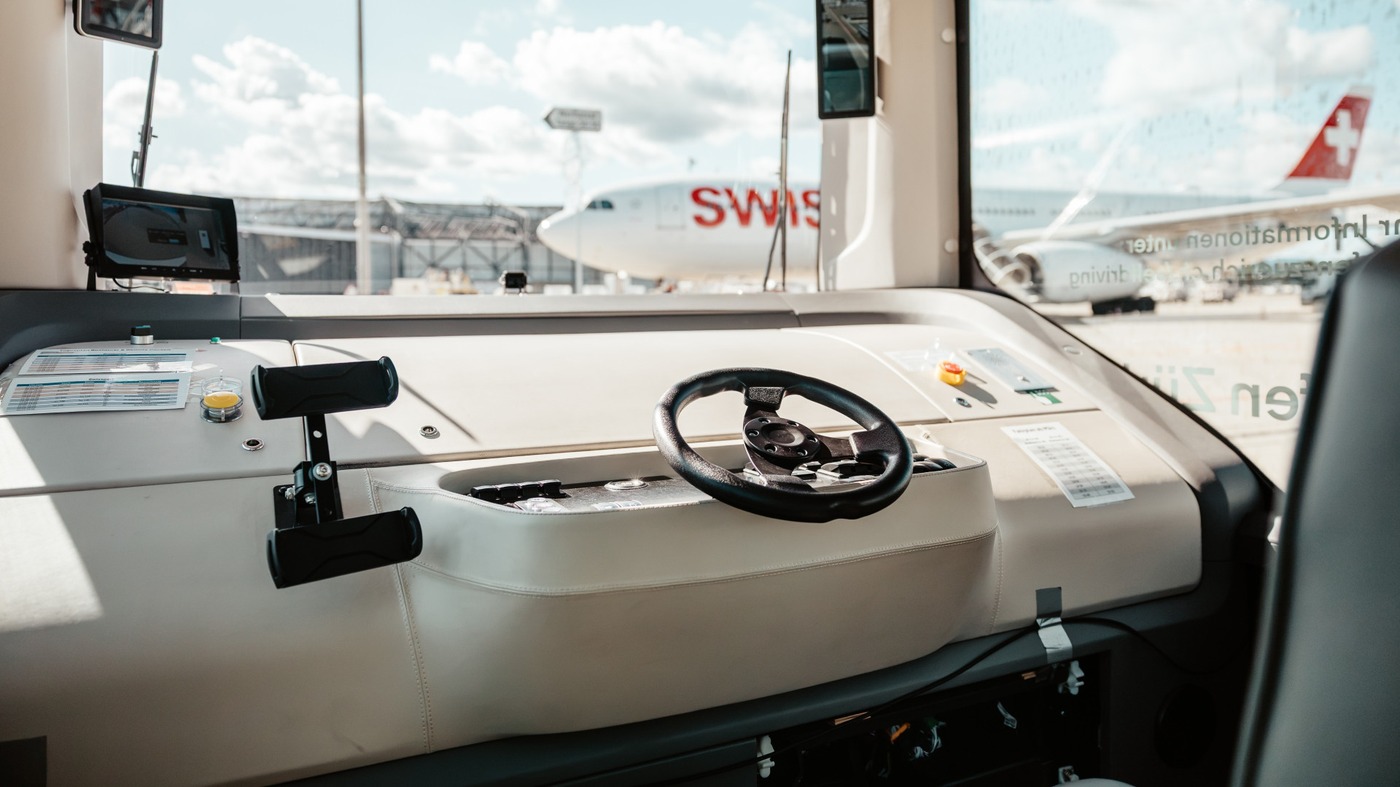 Cockpit of a WeRide autonomous shuttle at Zurich Airport, with a Swiss aircraft visible through the windshield.